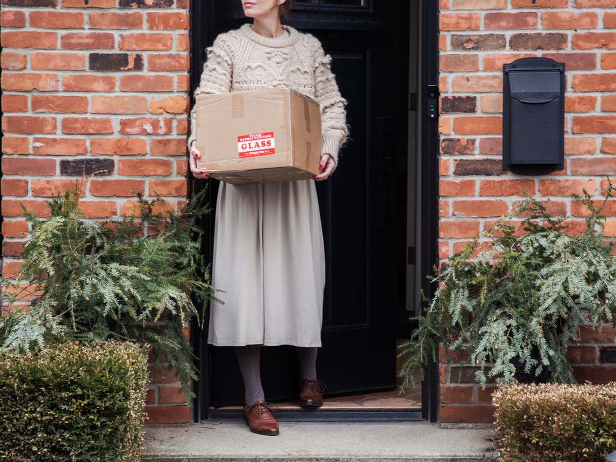 A woman carrying a box of donated goods to ship